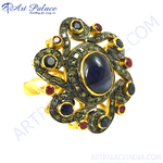 Load image into Gallery viewer, Oxidized gold ring featuring a large sapphire center stone and ruby accents in a floral design.