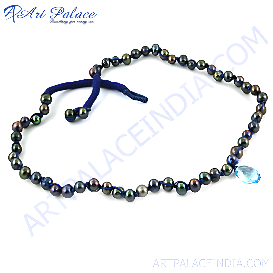 Black pearl necklace with a blue topaz gemstone pendant, strung on a dark blue cord.