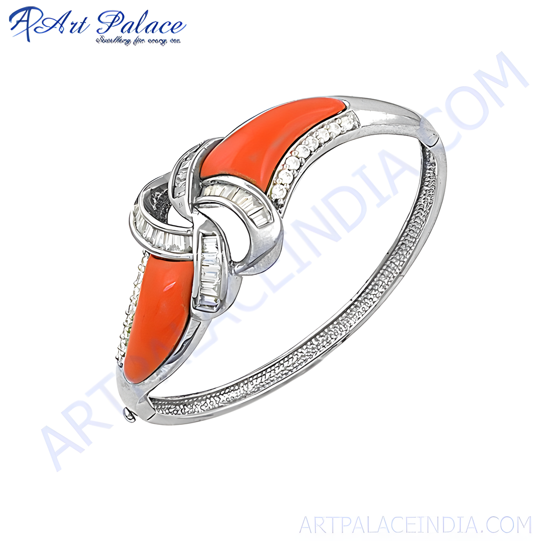 Silver bangle bracelet featuring a central coral stone and diamond accents, a beautiful piece of luxury jewelry.